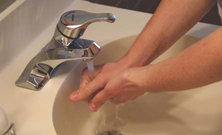 person washing hands under water faucet